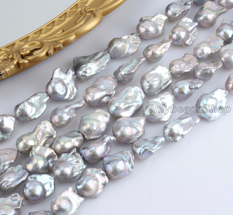 May include: A strand of grey baroque freshwater pearls. The pearls are irregular in shape and have a slightly iridescent sheen.