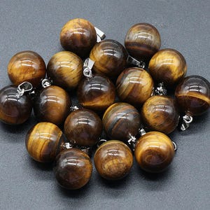 May include: A collection of 16 round tiger's eye gemstone beads with silver jump rings. The beads are a mix of brown and gold colors.