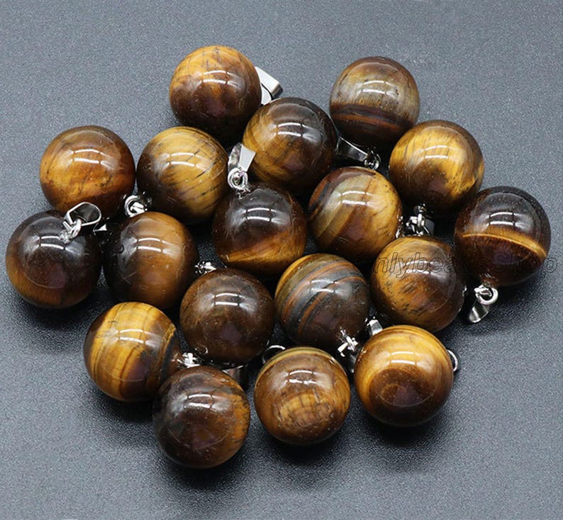 May include: A collection of 16 round tiger's eye gemstone beads with silver jump rings. The beads are a mix of brown and gold colors.