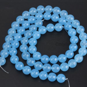 May include: A strand of light blue round gemstone beads. The beads are smooth and polished, and they are strung on a clear thread.