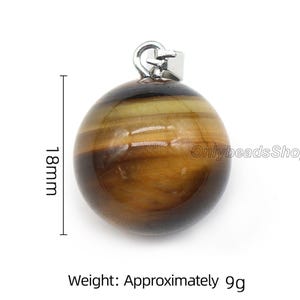 May include: A round, brown and gold tiger's eye gemstone pendant with a silver bail. The pendant measures 1.8 inches in diameter and weighs approximately 9 grams.