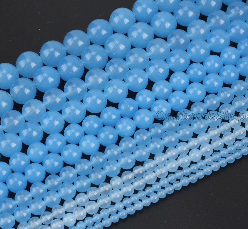 May include: A strand of light blue round gemstone beads in various sizes. The beads are smooth and polished, with a translucent appearance.