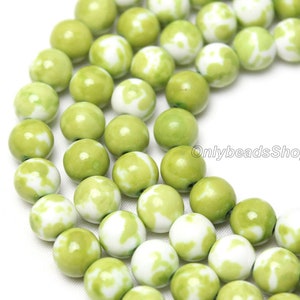 May include: A strand of green and white ceramic beads. The beads are round and have a marbled pattern.