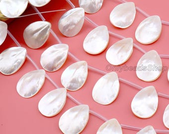 May include: White, teardrop-shaped mother-of-pearl beads strung together. The beads have a pearlescent sheen and are arranged on a pink surface. The beads are approximately 1 inch in length, and are ideal for jewelry making.