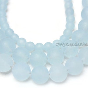 May include: A strand of light blue frosted glass beads. The beads are round and have a matte finish.