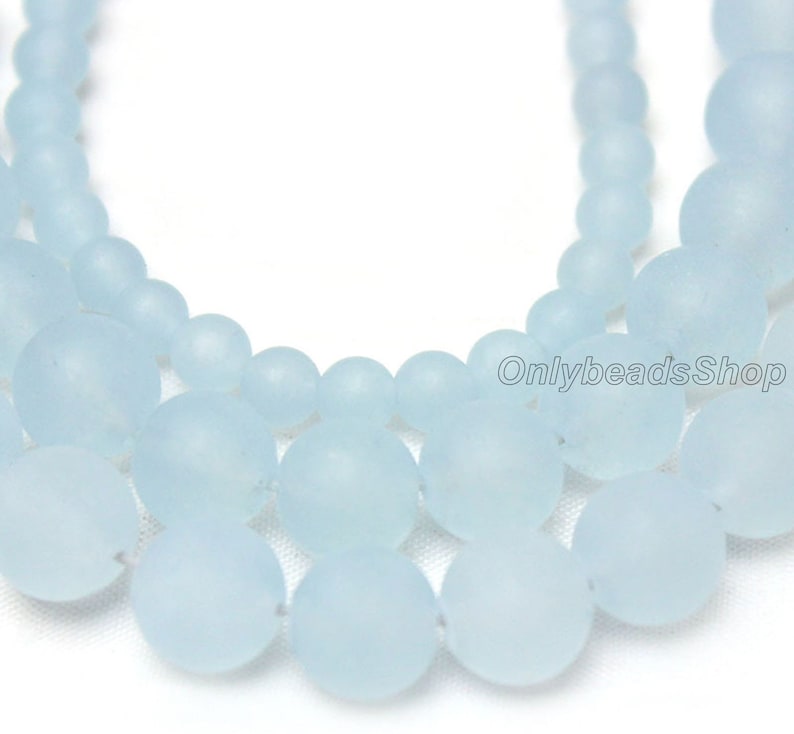 May include: A strand of light blue frosted glass beads. The beads are round and have a matte finish.