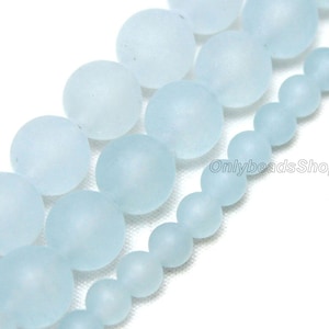 May include: A strand of frosted glass beads in various sizes, ranging from small to large. The beads are a light blue color and have a smooth, matte finish. The beads are strung together on a clear thread.