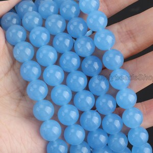 May include: A strand of light blue round beads. The beads are smooth and have a slightly translucent appearance.