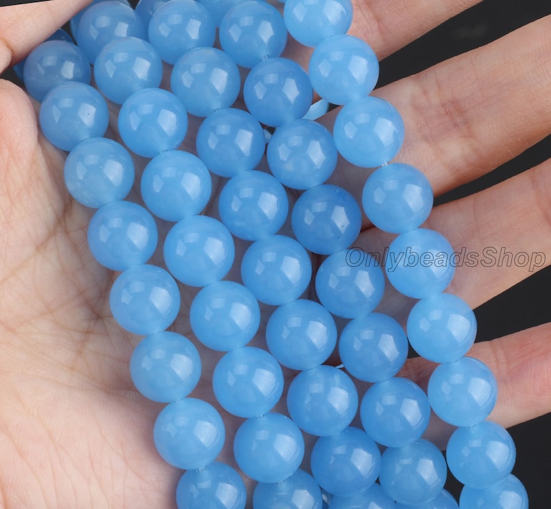 May include: A strand of light blue round beads. The beads are smooth and have a slightly translucent appearance.