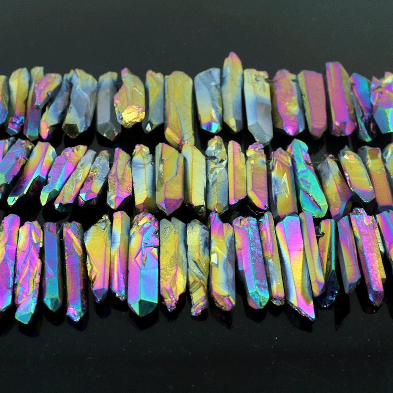 K&ouml;nnte beinhalten: Eine Str&auml;hne aus irisierenden, facettierten, schwarzen Quarzkristallspitzen. Die Spitzen sind etwa 2,5 cm lang und haben einen Regenbogen-Schimmer.