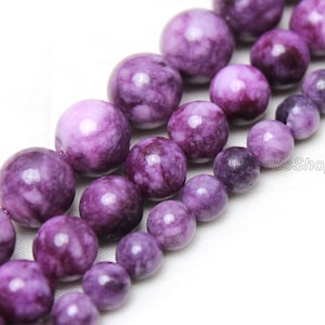 May include: A strand of purple and white agate beads. The beads are round and have a smooth, polished finish. The beads are strung on a clear elastic cord.