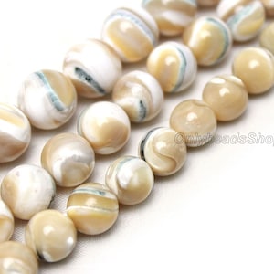 May include: A strand of round, white and beige shell beads with brown and green swirls. The beads are approximately 10mm in diameter.