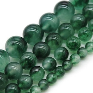 May include: A strand of green jade beads, each bead is round and has a mottled green color.