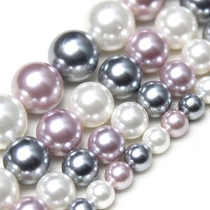 Può includere: Un filo di perle rotonde in bianco, grigio e rosa. Le perle hanno una finitura liscia e lucida.