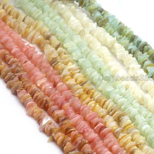 Puede incluir: Hilos de cuentas de piedras preciosas de colores, de forma irregular, en tonos rosa, melocotón, amarillo, verde y blanco. Las cuentas están ensartadas, creando una apariencia texturizada y natural. La imagen está bien iluminada, mostrando la variedad de colores y texturas.