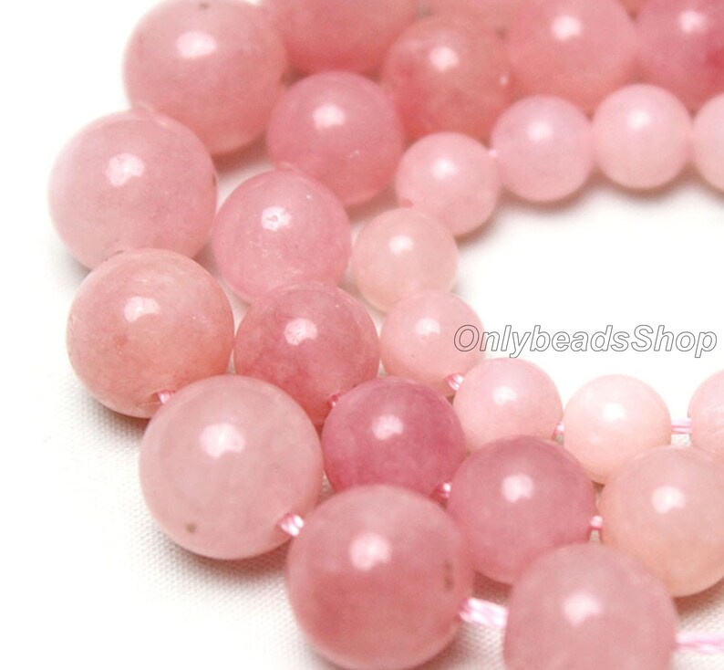 May include: A strand of pink rose quartz beads. The beads are round and smooth, and they have a natural, polished finish. The beads are strung on a clear elastic cord.