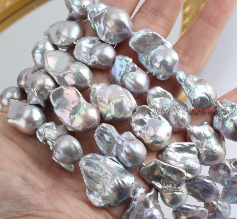 May include: A strand of baroque freshwater pearls in a silvery grey colour with iridescent highlights. The pearls are irregular in shape and have a natural, organic look.