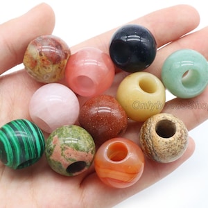 Könnte beinhalten: Sortiment von 10 runden Edelsteinperlen mit Löchern in der Mitte. Die Perlen sind in verschiedenen Farben, darunter rosa, grün, braun, rot und schwarz. Die Perlen haben einen Durchmesser von etwa 2,5 cm.