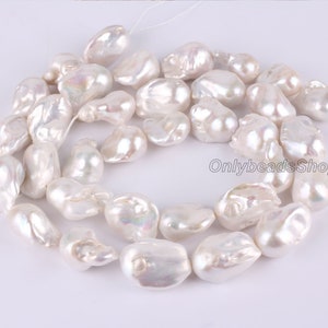 Peut inclure: Un brin de perles baroques blanches, avec un &eacute;clat iridescent. Les perles sont de forme et de taille irr&eacute;guli&egrave;res, et sont enfil&eacute;es sur un fil blanc.