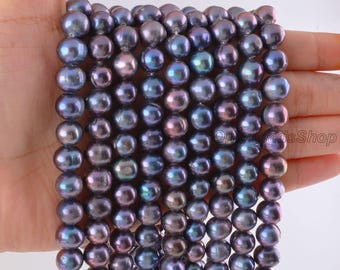 Puede incluir: Una colección de perlas redondas de color púrpura oscuro y azul iridiscente dispuestas en múltiples hilos verticales. Las perlas exhiben una superficie lisa y reflectante con sutiles variaciones de color, creando una apariencia profunda y lustrosa.
