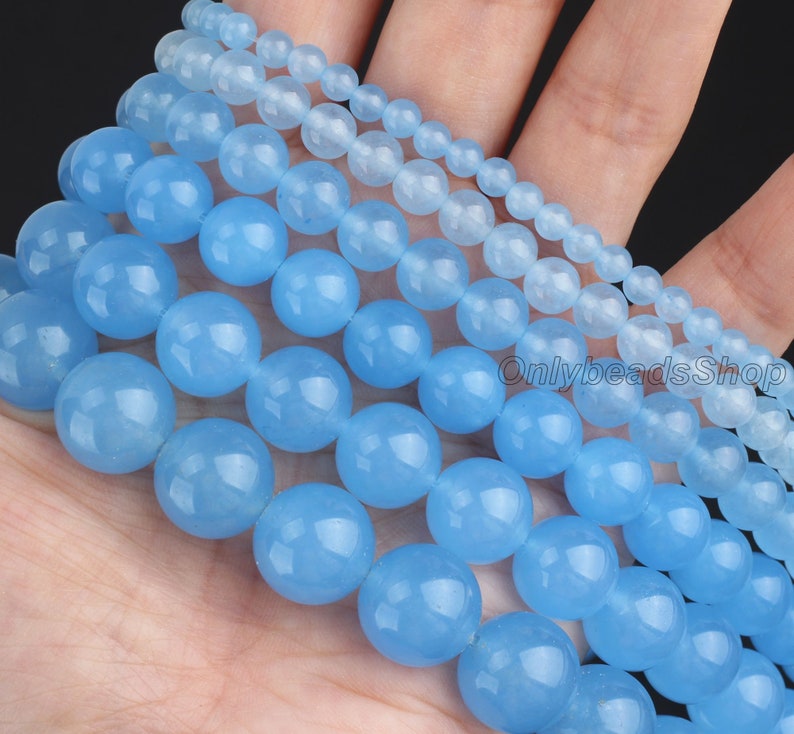 May include: A set of six strands of light blue round gemstone beads. The beads are of varying sizes, with the largest beads being approximately 2.5 cm in diameter. The beads are smooth and polished, and they have a translucent appearance.