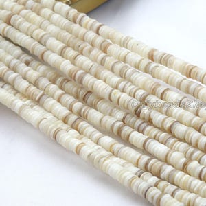 Op de afbeelding: Close-up van meerdere strengen platte, ronde kralen in crème- en bruintinten. De kralen zijn uniform van grootte en vorm, waardoor een textuur ontstaat. Geschikt voor het maken van sieraden en diverse knutselprojecten.