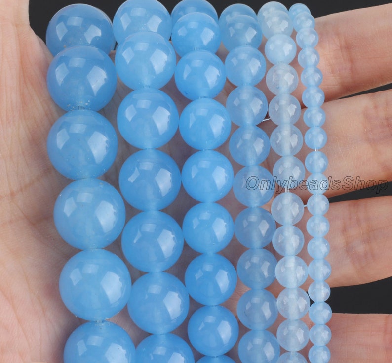May include: Assortment of light blue round gemstone beads in various sizes. The beads are smooth and polished, with a translucent appearance.