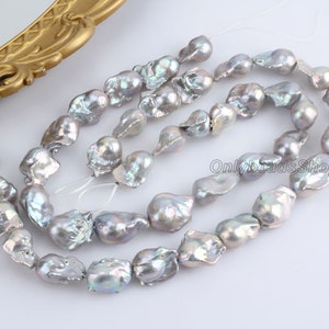 May include: A strand of iridescent grey freshwater pearls. The pearls are irregular in shape and have a natural, organic look. They are strung on a white thread and are ready to be used in jewellery making.