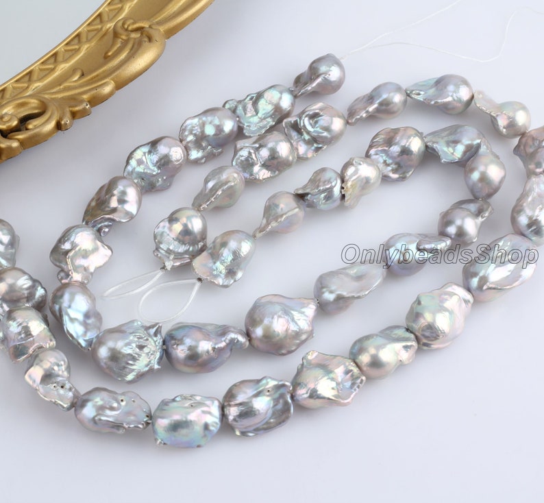 May include: A strand of iridescent grey freshwater pearls. The pearls are irregular in shape and have a natural, organic look. They are strung on a white thread and are ready to be used in jewellery making.