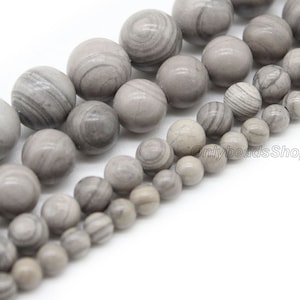 Könnte beinhalten: Eine Strähne aus grauen und weißen, gestreiften runden Perlen. Die Perlen sind aus Naturstein und haben eine glatte, polierte Oberfläche.