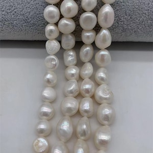 May include: A strand of white freshwater pearls, each pearl is a slightly irregular shape, with a smooth, glossy finish.