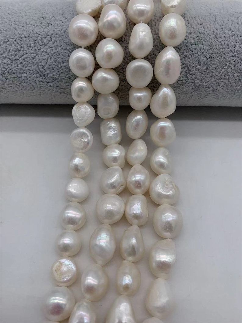 May include: A strand of white freshwater pearls, each pearl is a slightly irregular shape, with a smooth, glossy finish.