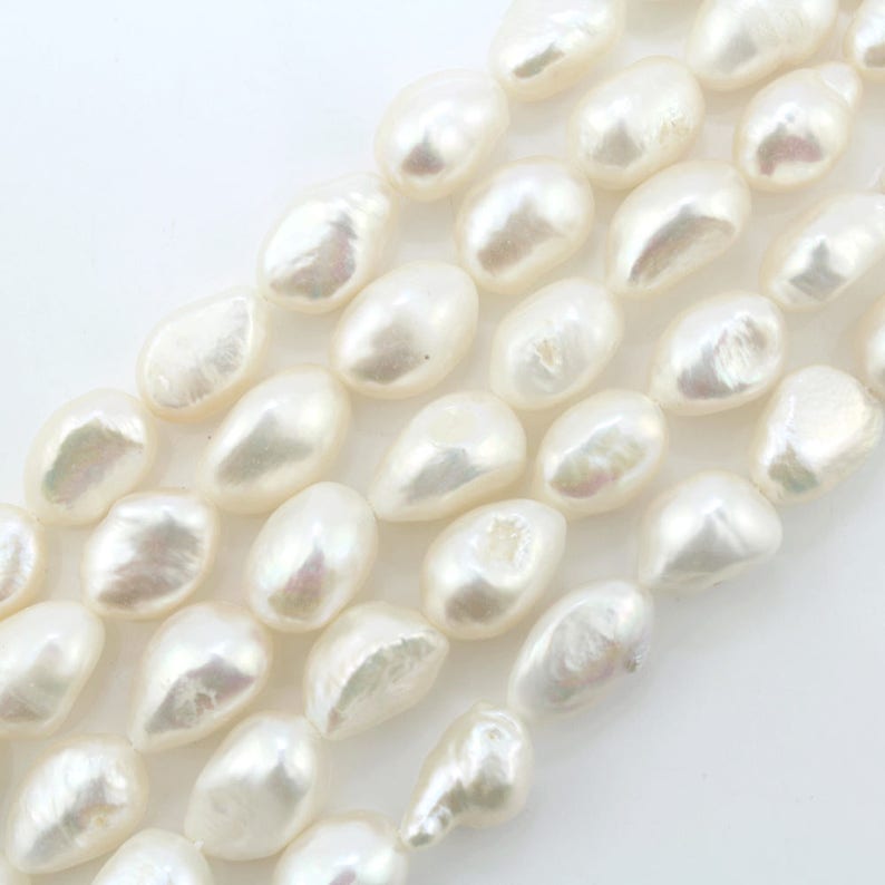 May include: A strand of white freshwater pearls, with a smooth, oval shape. The pearls are arranged in a loose, flowing pattern, creating a delicate and elegant look.