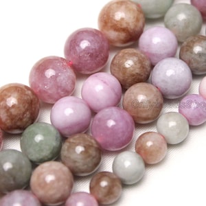 May include: A strand of pink, green, and brown gemstone beads. The beads are round and have a smooth, polished finish.