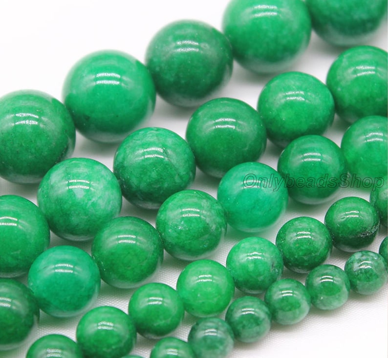May include: A strand of round, green jade beads. The beads are smooth and polished, with a slight variation in color and texture.