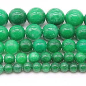 May include: A strand of green jade beads in various sizes. The beads are round and smooth, with a polished finish. The beads are arranged in rows, with the largest beads at the top and the smallest beads at the bottom.
