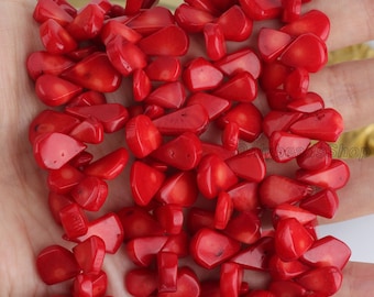 May include: A close-up of a pile of red coral beads. The beads are irregularly shaped and have a natural, organic look. They are perfect for making jewelry or other crafts.