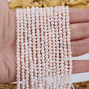 Può includere: Un filo di perle d'acqua dolce bianche, di circa 4-5 mm di dimensione, infilate su un filo bianco. Le perle sono rotonde e lisce, con una leggera lucentezza. Il filo è lungo circa 40 cm.