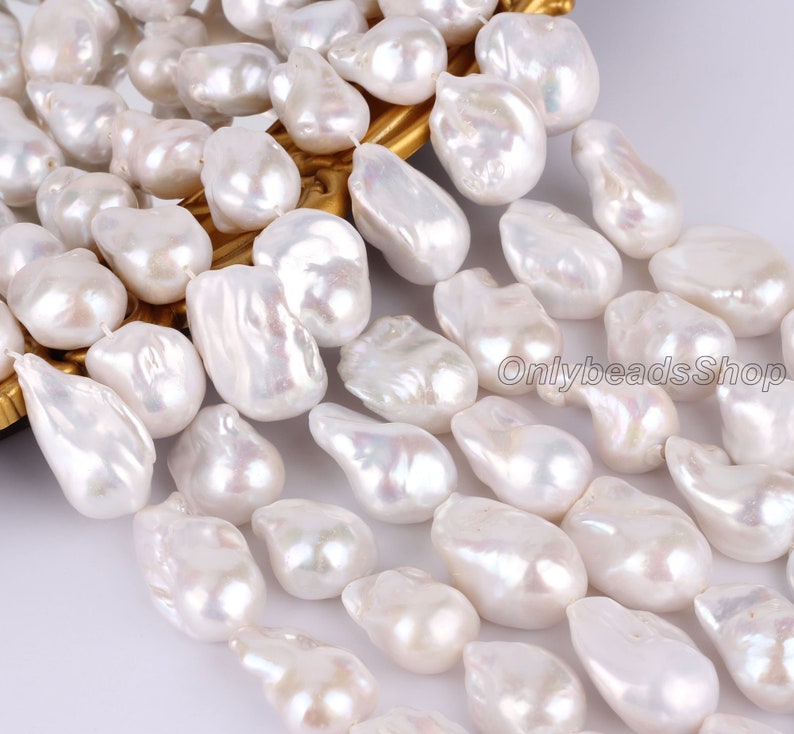 Peut inclure: Un brin de perles d'eau douce baroques blanches. Les perles sont de forme irr&eacute;guli&egrave;re et ont une finition lisse et lustr&eacute;e. Elles sont enfil&eacute;es sur un fil blanc et sont pr&ecirc;tes &agrave; &ecirc;tre utilis&eacute;es pour la fabrication de bijoux.