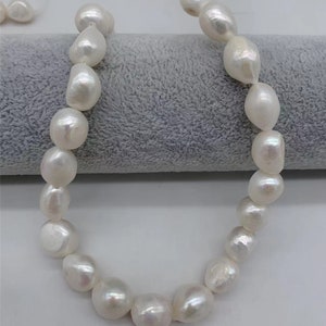 May include: A strand of white baroque pearls, each pearl is a different size and shape, with a slight iridescent sheen.