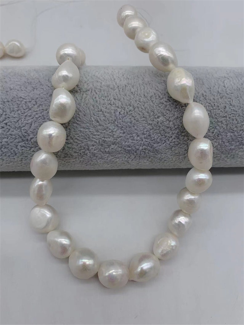 May include: A strand of white baroque pearls, each pearl is a different size and shape, with a slight iridescent sheen.