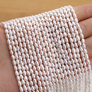 May include: Strands of white, oval-shaped pearls. The pearls are strung together, creating a dense, textured surface. The pearls are a creamy white color and appear to have a natural luster. The image is well-lit, highlighting the details of the pearls.