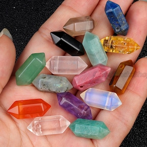 May include: Assortment of 14 gemstone point pendants in various colors, including clear, green, red, orange, purple, blue, and brown. The pendants are all in the shape of a point with a hole drilled through the top for stringing.