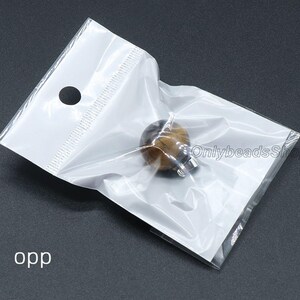May include: A small, round, tiger's eye bead with a silver clasp in a clear plastic bag. The bag has a hole at the top for hanging.