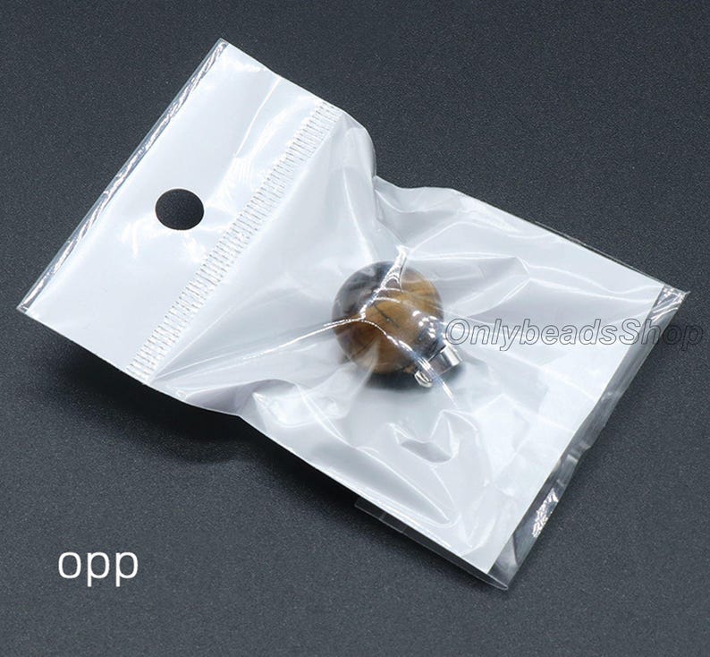 May include: A small, round, tiger's eye bead with a silver clasp in a clear plastic bag. The bag has a hole at the top for hanging.