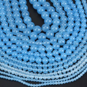May include: A collection of light blue gemstone beads in various sizes. The beads are round and smooth, with a polished finish.