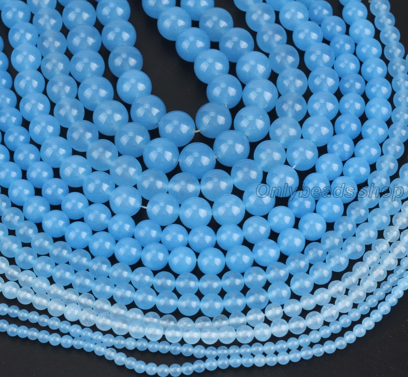 May include: A collection of light blue gemstone beads in various sizes. The beads are round and smooth, with a polished finish.