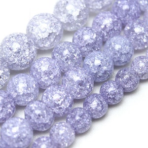 May include: A strand of round, iridescent, light purple glass beads with a crackled texture. The beads are strung on a clear thread.