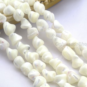 Peut inclure: Gros plan sur des rangées de perles irrégulières de couleur blanc cassé. Les perles ont un éclat nacré et une texture lisse. Les perles sont enfilées, créant un collier ou un bracelet. Les perles sont probablement faites de matériaux naturels.