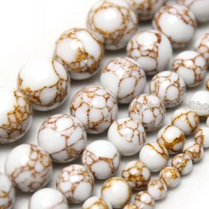 May include: White and gold round beads with a marbled pattern. The beads are strung together on a string.